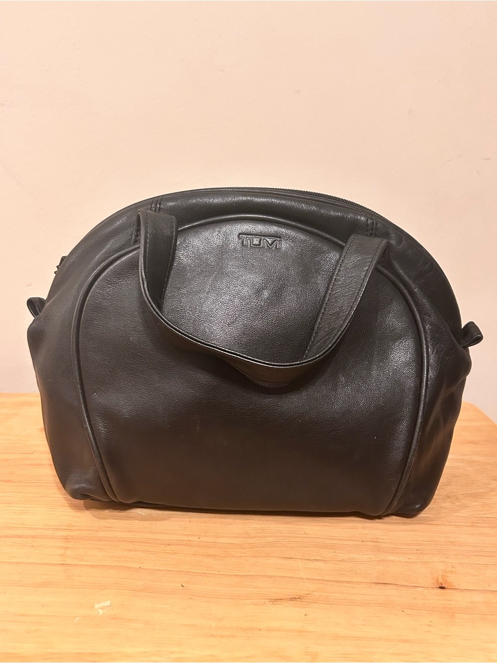 Vintage Tumi black leather dome satchel handbag featuring embossed branding.